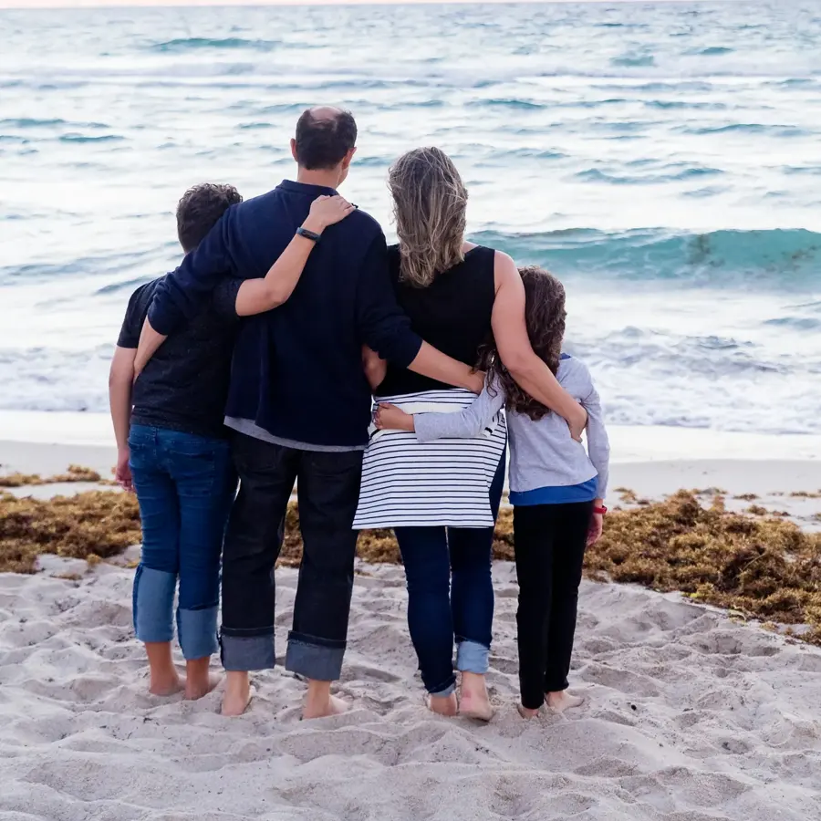 Família abraçada olhando o mar